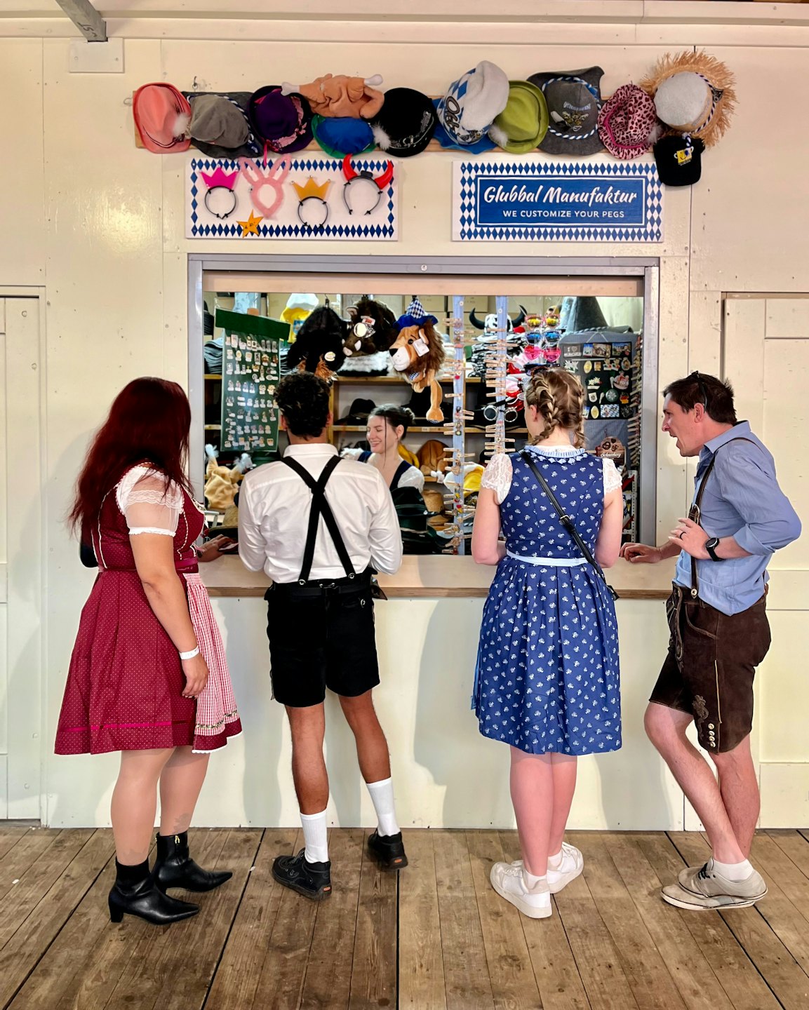 Menschen in Tracht begutachten Hüte an einem Marktstand.
