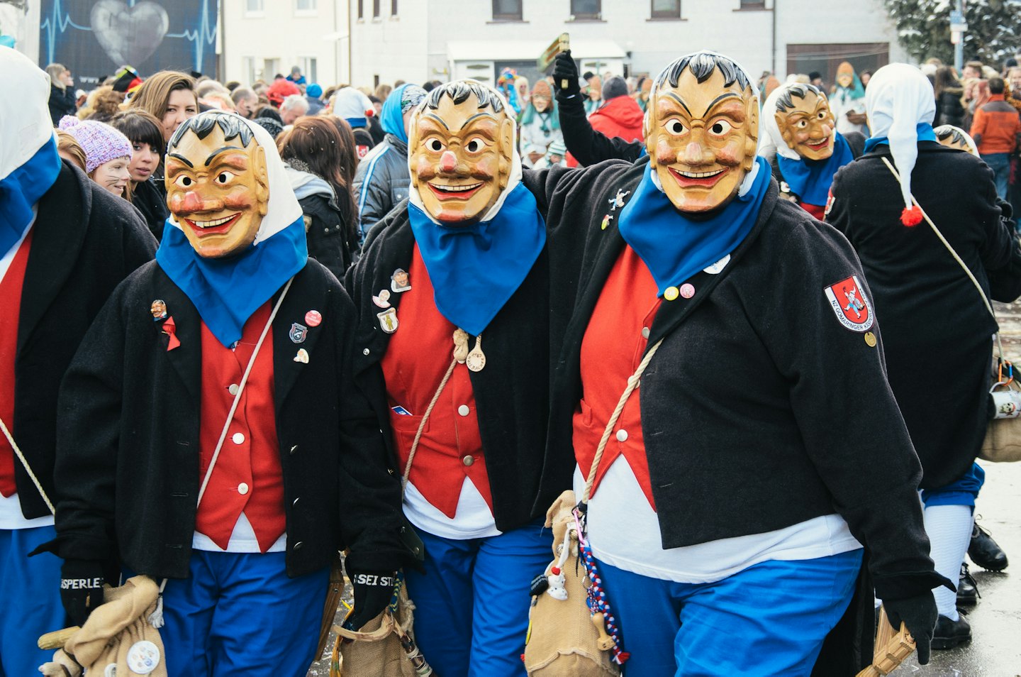 Menschen in deutschen Fasnets-Kostümen mit Masken und Taschen auf einem Fest.