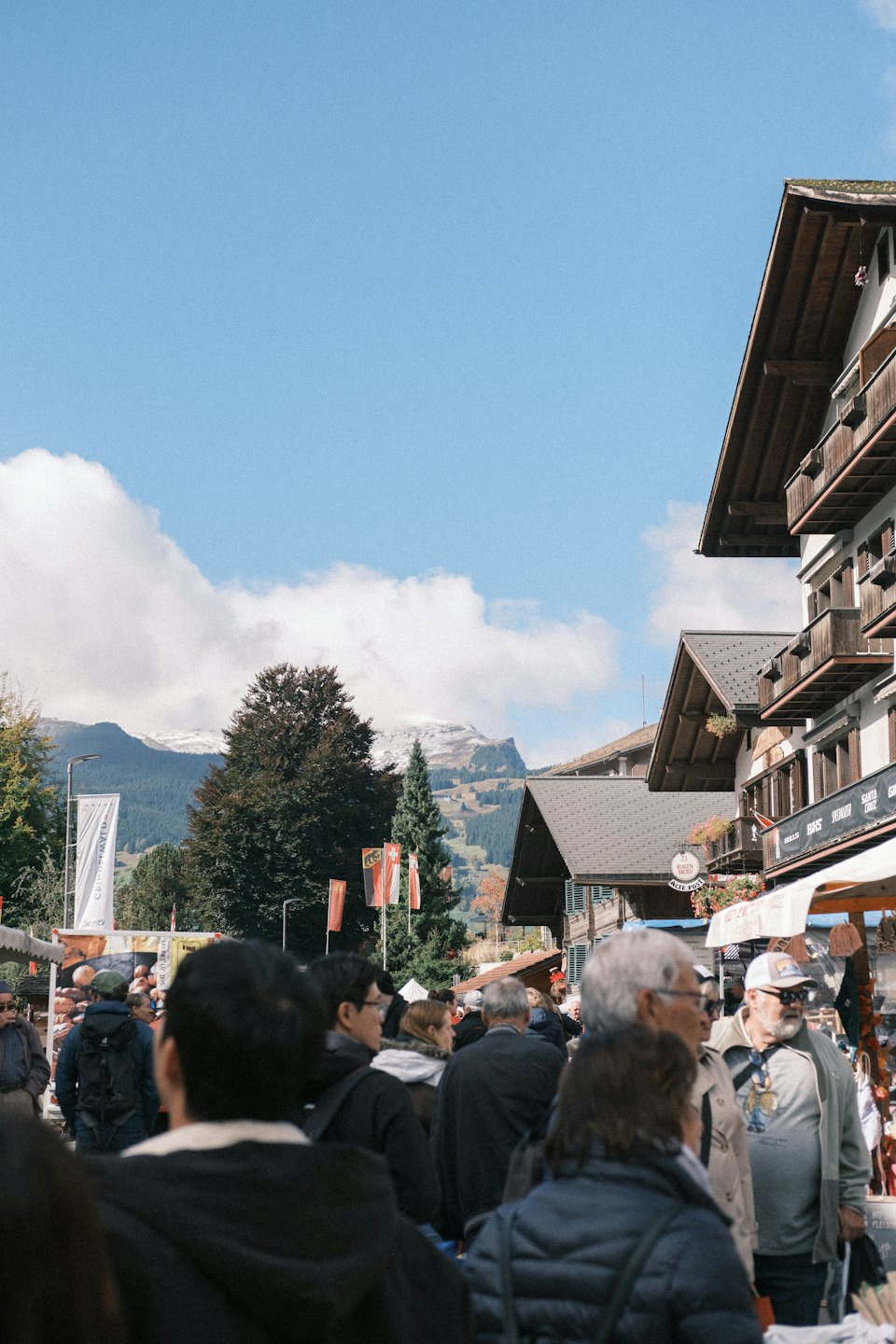 Menschen spazieren durch eine Alpenstadt mit schneebedeckten Bergen.