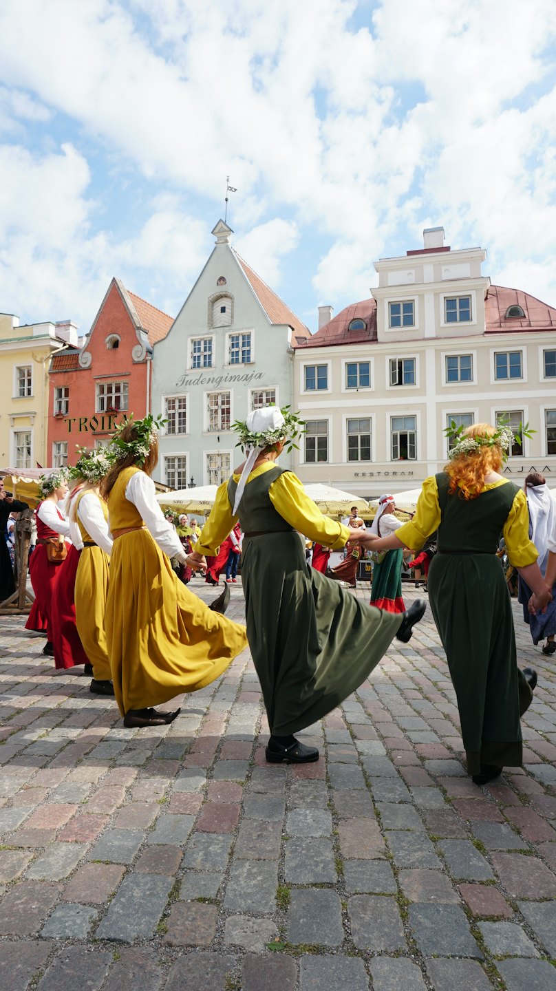Tänzer in traditionellen Kostümen halten Händchen und bewegen sich im Kreis.